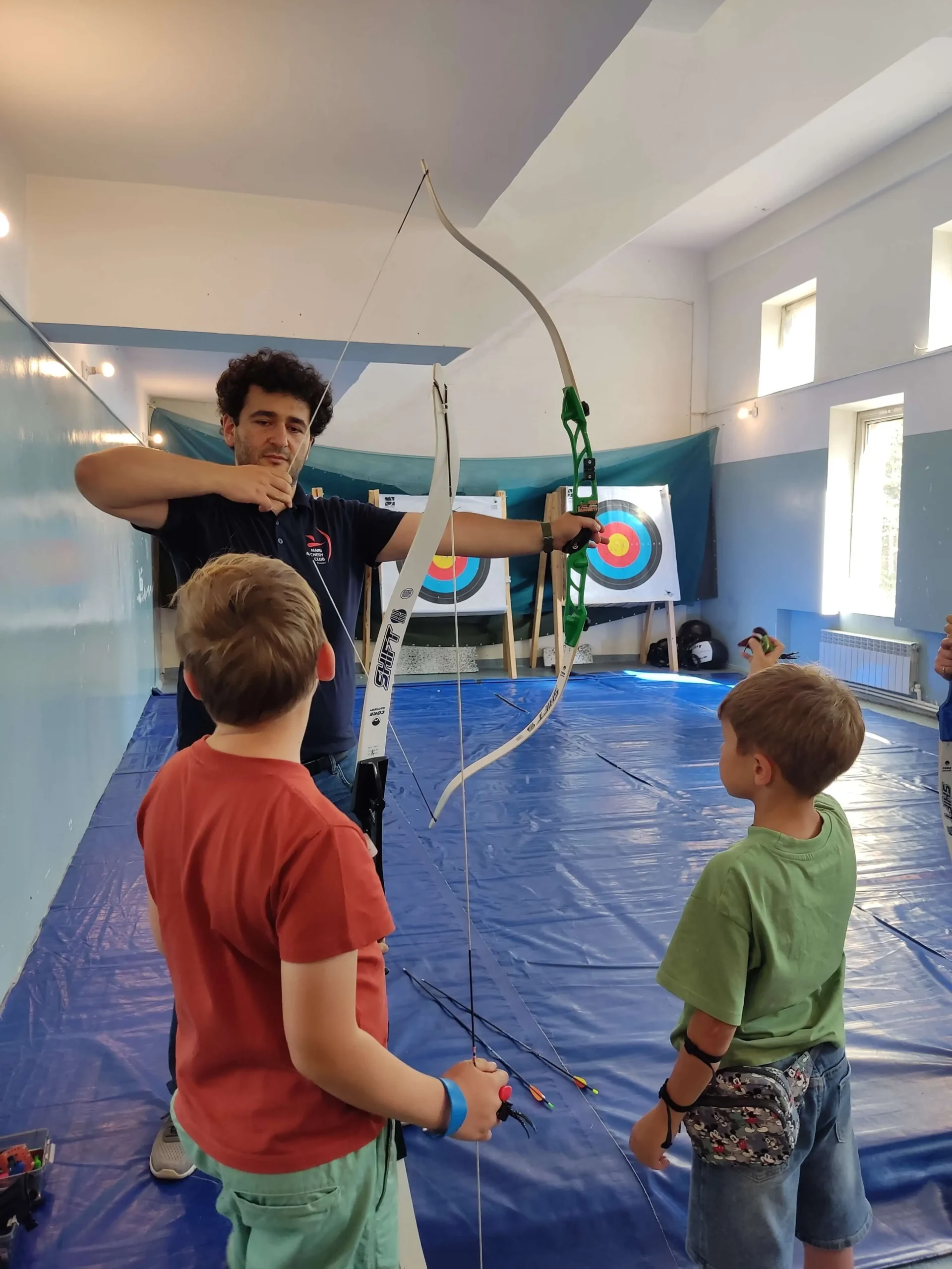 մարզիչը սովորեցնում է երեխաներին ինչպես նետարձակել