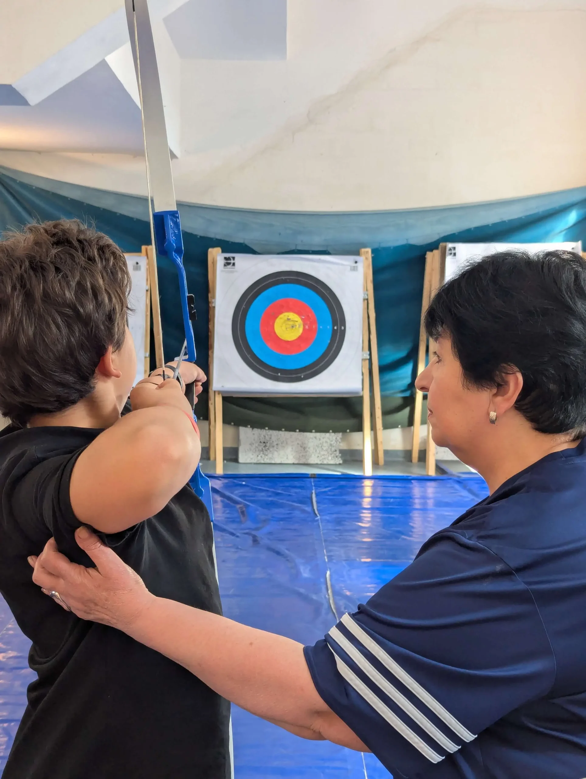 մարզիչը օգնում է երեխային նետարձակել